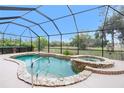 Screened-in pool and spa with stone accents and a view of the lush green backyard at 21 Manizaks Ave, Punta Gorda, FL 33983
