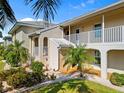Inviting condo exterior with landscaped yard, white railings, beige paint, and tropical foliage at 220 Coldeway Dr # 211, Punta Gorda, FL 33950