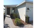 Home exterior view featuring a covered entrance, manicured shrubs, brick paver walkway, and neutral paint at 43735 Cattleman Dr, Punta Gorda, FL 33982