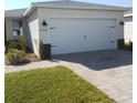 Front exterior showcasing a two car garage, manicured lawn, brick paver driveway, and neutral paint at 43735 Cattleman Dr, Punta Gorda, FL 33982