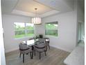 Well-lit dining area with a modern chandelier, large windows, and a glass-top table with seating for four at 9529 Calumet Blvd, Port Charlotte, FL 33981