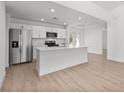 Open kitchen features stainless steel appliances, an island with seating, and wood-look flooring at 111 Swan Dr, Rotonda West, FL 33947