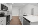 Bright kitchen featuring stainless steel appliances, quartz counters, an island with sink, and wood-look flooring at 111 Swan Dr, Rotonda West, FL 33947