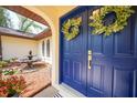 Close-up of a blue front door featuring decorative wreaths and a charming fountain in the entryway at 22092 Bombay Ave, Port Charlotte, FL 33952