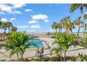 Scenic view of a refreshing pool surrounded by palm trees and lush landscaping, leading to a sandy beach at 1212 Benjamin Franklin Dr # 102, Sarasota, FL 34236
