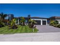 Beautiful modern home features meticulous landscaping, a wide driveway, and a two-car garage under a clear blue sky at 1230 Royal Tern Dr, Punta Gorda, FL 33950