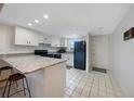 Kitchen featuring white cabinets, a breakfast bar, white tile flooring, and black appliances at 179 Boundary Blvd # 4, Rotonda West, FL 33947
