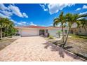 Charming single-story home with a tile roof, palm trees, and a patterned driveway, offering curb appeal at 1791 Belle Ct, Punta Gorda, FL 33950