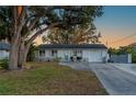 Charming single-story home with a well-maintained lawn, mature tree, and a long driveway leading to a one-car garage at 18417 Ohara Dr, Port Charlotte, FL 33948