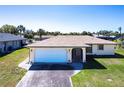 Charming single-story home with a well-manicured lawn, a paved driveway, and an attached two-car garage at 18462 Alphonse Cir, Port Charlotte, FL 33948