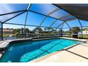 Screened-in pool area with clear blue water and a view of the canal and dock, great for relaxing outdoors at 18462 Alphonse Cir, Port Charlotte, FL 33948