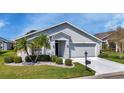 Charming one-story home with lush landscaping, featuring a well-manicured lawn, palm trees, and decorative shrubbery at 24055 Buckingham Way, Punta Gorda, FL 33980