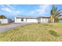 Single-story home with a white exterior, concrete driveway, and well-maintained lawn on a sunny day at 3243 Elkcam Blvd, Port Charlotte, FL 33952