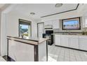 Bright kitchen with white cabinets, a marble countertop peninsula, and black appliances and window trim at 3243 Elkcam Blvd, Port Charlotte, FL 33952