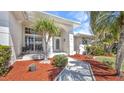 Charming home entrance with a paved walkway surrounded by palm trees and mulch at 412 Panarea Dr, Punta Gorda, FL 33950