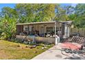 A rear exterior shot shows the back of a house with a screen porch with a grass yard and surrounding trees at 4645 80Th N St, St Petersburg, FL 33709