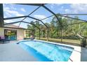 Inviting screened-in pool area with clear blue water, surrounded by a patio and lush landscaping at 5125 Ariton Rd, North Port, FL 34288