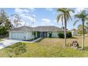 Lovely one-story home with an attached three-car garage, mature palm trees, and a grassy yard at 535 Ramblewood St, Port Charlotte, FL 33953