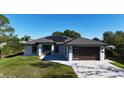 Inviting single-story home with modern garage door, solar panels and lush green lawn at 7344 Manthey Ave, North Port, FL 34291