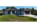 Charming single-story home featuring a modern garage door, solar panels, and a well-manicured lawn at 7344 Manthey Ave, North Port, FL 34291