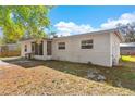 Neutral-painted single-story home with a screened-in entryway, surrounded by a grassy yard with bright skies overhead at 102 21St Ne St, Bradenton, FL 34208
