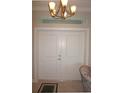 Elegant interior double doors with modern chandelier and transom window above, creating a grand entrance at 1182 Yorkshire St, Port Charlotte, FL 33952