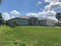 A side view of a well-maintained home with lush green lawn and mature landscaping in a sunny neighborhood at 1182 Yorkshire St, Port Charlotte, FL 33952