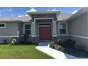 Inviting front entrance with stone accents, a charming red double door and lovely landscaping at 1182 Yorkshire St, Port Charlotte, FL 33952