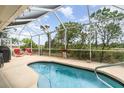 Relaxing screened-in pool area featuring a sparkling pool, lounge chairs, and lush greenery at 145 Brig E Cir, Placida, FL 33946