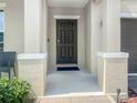 Covered front porch featuring a dark front door, white columns, and space for seating at 15172 Mcgraw Ave, Port Charlotte, FL 33953