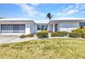 Single-story home featuring a white exterior, tidy landscaping, and a modern garage door at 2350 W Marion Ave, Punta Gorda, FL 33950