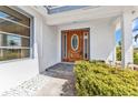 Inviting home entrance featuring a wood door, decorative sidelights, and manicured landscaping at 2350 W Marion Ave, Punta Gorda, FL 33950