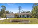 Inviting single-story home featuring a manicured lawn and a colorful flower bed, adding charm to the property at 2631 Tomaso Rd, North Port, FL 34287