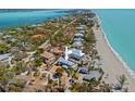 Stunning aerial view of coastal home near pristine beach with turquoise waters and lush palms at 6112 Gnarled Oak Dr, Englewood, FL 34223