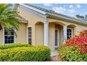 Close-up of the house featuring an arched entry with white columns and flowering bushes at 9020 Eagle Bay Ct, North Port, FL 34287