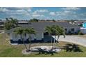 Charming home with manicured lawn and palm trees, featuring a long driveway and vibrant blue trim accents at 234 Tait Se Ter, Port Charlotte, FL 33952