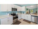 Bright kitchen features white cabinets, stainless steel appliances, and tile flooring at 25292 E Lenox Cir, Punta Gorda, FL 33950