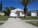 Quaint one-story home featuring a well-kept lawn and a paved driveway at 409 Ricold Ter, Port Charlotte, FL 33954