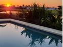 Beautiful pool reflecting a brilliant sunset and tropical plants at 82 Caddy Rd, Rotonda West, FL 33947