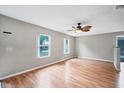 Spacious living room featuring hardwood floors, two windows, and a modern ceiling fan at 8706 Fish Lake Rd, Tampa, FL 33619