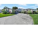 A lovely single-story home has a well-manicured lawn, lush landscaping, and a circular driveway at 955 Don Juan Ct, Punta Gorda, FL 33950