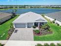 Aerial view of a single-story home with a three-car garage in a lakeside community, surrounded by lush green lawns at 16064 Shoreline Dr, Punta Gorda, FL 33982