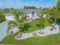 Beautiful single-story home with a manicured lawn, palm trees, and decorative rock landscaping at 2095 Ellery St, Port Charlotte, FL 33952