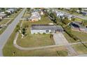 An aerial view of a cozy single-story home with a well-kept lawn, neighborhood street, and community at 2201 Birchcrest Blvd, Port Charlotte, FL 33952