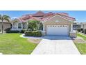 Single-story home with a lush front lawn, two-car garage, and tropical landscaping leading to the front door at 341 Segovia Dr, Punta Gorda, FL 33950