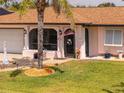 Inviting home with a well-manicured lawn, palm tree, and charming decor at 4114 Yucatan Cir, Port Charlotte, FL 33948