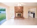 Cozy living room with a brick fireplace, sliding glass door to outside, and tile floors throughout at 536 Lakehurst Nw Ave, Port Charlotte, FL 33952