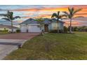 Charming single-story home featuring a brick driveway, two-car garage, and well-maintained lawn at sunset at 7028 N Plum Tree, Punta Gorda, FL 33955
