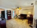 Cozy living room with plush brown carpeting, ceiling fan, and lots of natural light from the large window at 1148 Barbour Ave, Port Charlotte, FL 33948