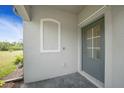 Close-up of the front door of the home, showcasing the light gray paint and adjacent wall fixture at 2232 Bonito Way, Port Charlotte, FL 33953